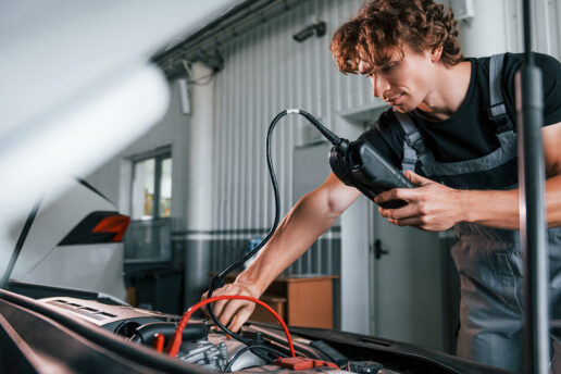 Technician performing ABS diagnostics on car with handheld diagnostic tool at Nottingham Auto Electrics workshop.