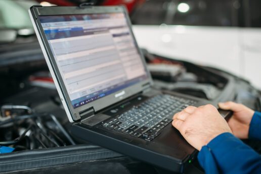 Engine Management Diagnostics Technician performing engine management diagnostics on car using laptop at Nottingham Auto Electrics workshop